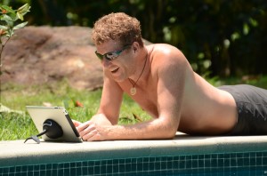 Man relaxes poolside while enjoying his iPad with new iPad stand