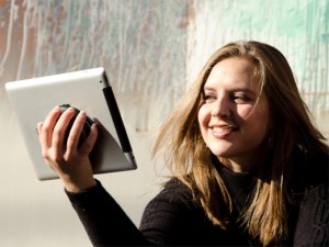 A woman holds a tablet with the Whale Kit iPad holder which also works great with a Kindle or other e-readers.