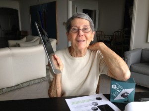 Elderly woman holds up her iPad with her new iPad stand: The Octa Whale Kit.